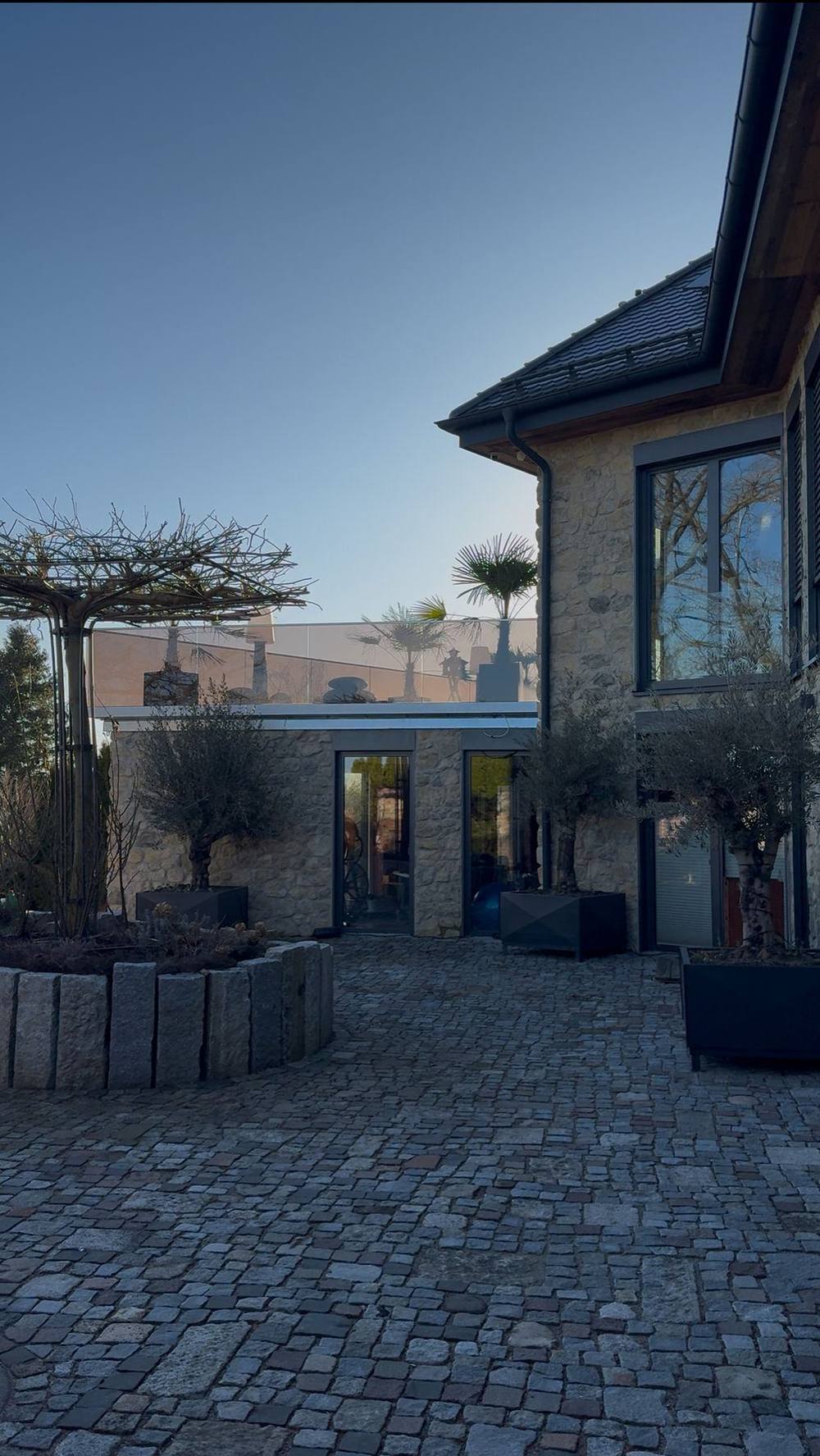 Gepflegter Innenhof mit Natursteinfassade, Pflaster und Bepflanzung